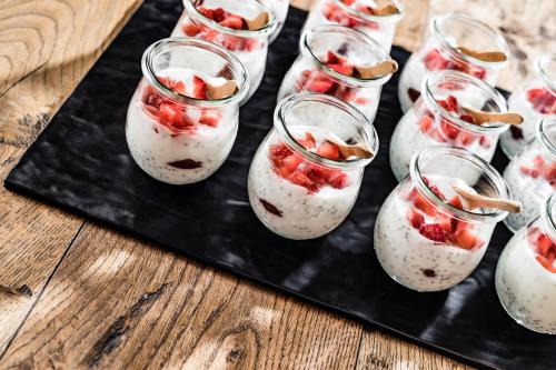 a group of glasses filled with strawberry overnight oats on a black tray at Engels Park in Vipiteno