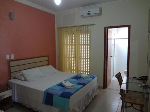 um quarto com uma cama, uma secretária e uma janela em Itália Hotel em Fernandópolis