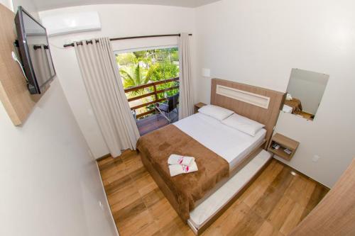 a small bedroom with a bed and a balcony at Pousada Rosa in Penha