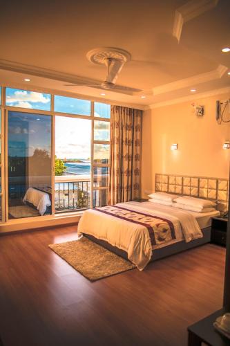 a bedroom with a large bed and a large window at Abuharee Grand in Hithadhoo