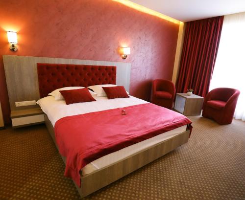 a hotel room with a large bed and two chairs at MELISS EVENTS in Craiova