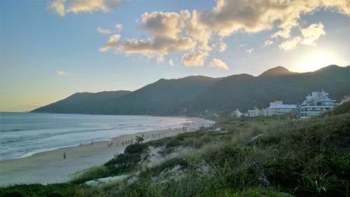 una playa con gente caminando por la arena y el océano en Mahalo Happy Apartment, en Florianópolis