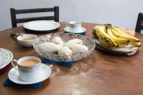 a table with plates and cups of coffee and bananas at Amma's Homestay in Kandy