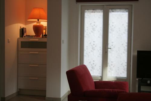 a living room with a red chair and a window at Gîtes du Tilleul in Niederbronn