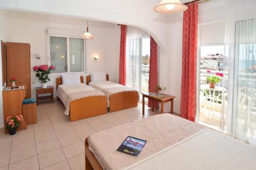 a hotel room with two beds and a balcony at Hotel TRIADA in Limenaria