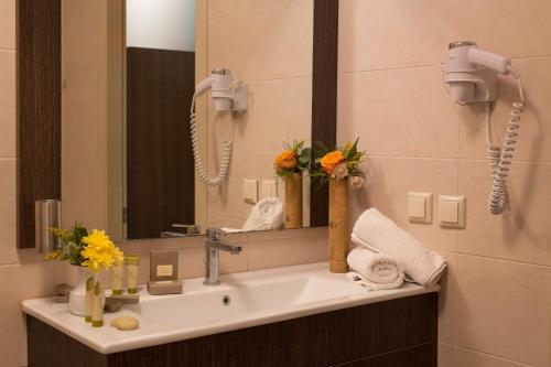 a bathroom with a sink with a mirror and flowers at Sunrise Resort Hotel in Mithymna