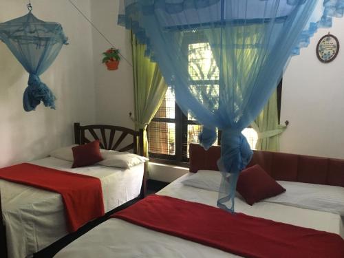 a room with two beds and a window with curtains at Araliya Home Stay in Kandy