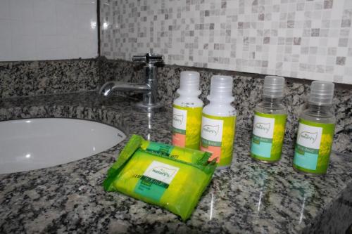 three bottles of disinfectants sitting on a bathroom sink at Hotel Marina Do Lago in Santa Cruz da Conceição