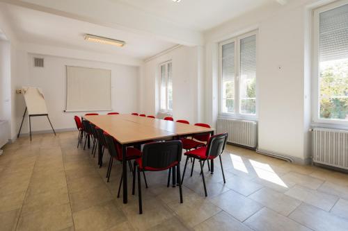 a conference room with a wooden table and red chairs at Hotel de Champagne in Saint-Dizier