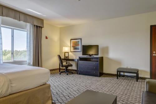 a hotel room with a bed and a desk with a television at Holiday Inn Poplar Bluff by IHG in Poplar Bluff