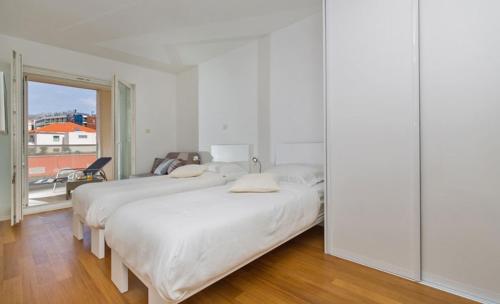 two beds in a white room with a window at Dubrovnik Luxury Apartment Lapad in Dubrovnik