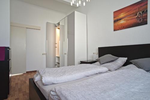 a bedroom with a large bed with white sheets at City Apartment Mendig in Mendig