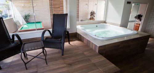 a bath tub in a room with two chairs and a table at Apto no Serra Madre Residence in Rio Quente