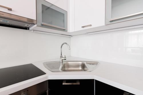 a kitchen with a sink and white cabinets at Stylish New Town Apartments in Prague