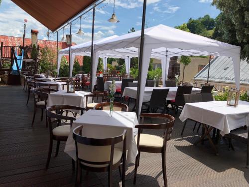 a restaurant with white tables and chairs with white umbrellas at Hotel & Penzión Grand Matej in Banská Štiavnica