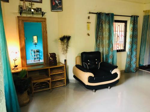 a living room with a chair and a mirror at Cozy Dream Apartment in Anjuna