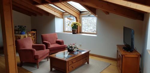 a living room with two chairs and a flat screen tv at Casa Rural Tío Carlillos in Hoyos del Espino