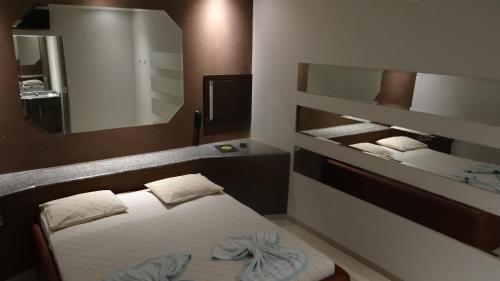 mały pokój z łóżkiem i lustrem w obiekcie Delirio Moteis Pousada w mieście Dourados