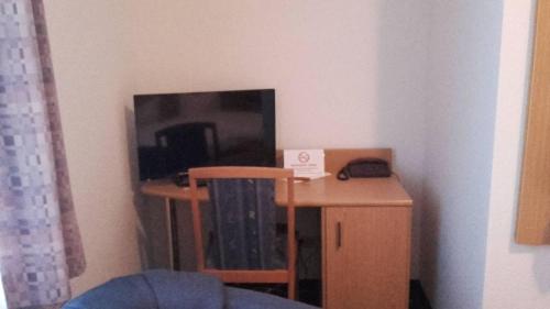 a small desk with a tv and a table with a chair at Hotel Goldenes Schiff in Grimma