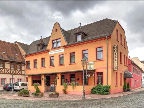 un edificio naranja con techo negro en una calle en Hotel Goldenes Schiff en Grimma