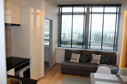 ein Wohnzimmer mit einem Sofa und zwei großen Fenstern in der Unterkunft Apartamenty A&B Gold in Kalisz