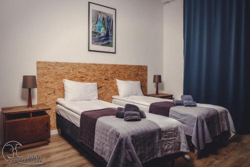 2 camas en una habitación de hotel con cortinas azules en Apartamenty 21, en Szczecin