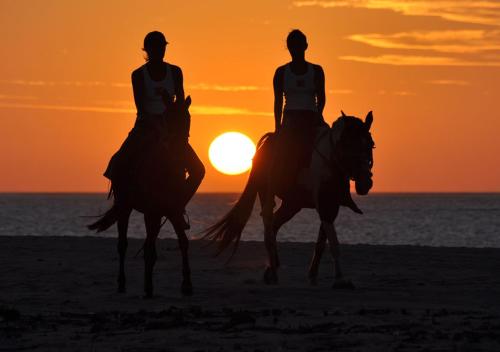 two women riding horses on the beach at sunset at Chic Hotel Boutique in Barra Grande