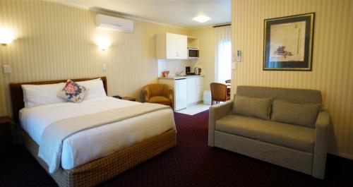 une chambre d'hôtel avec un lit et une chaise dans l'établissement Cornwall Park Motor Inn, à Auckland