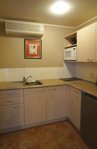 a kitchen with white cabinets and a sink and a microwave at Cornwall Park Motor Inn in Auckland