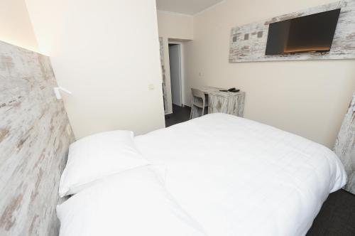 a bedroom with a white bed and a tv at Il Piccolo Mondo in Luxembourg