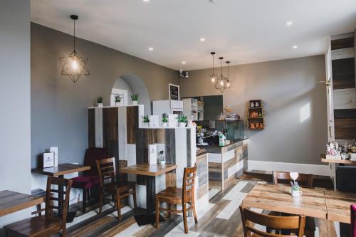 um restaurante com mesas e cadeiras de madeira e uma cozinha em Chapel Cross Guesthouse em Roslin