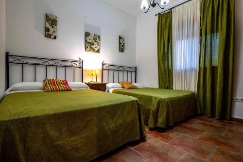 a bedroom with two beds with green sheets and a window at La Sierrezuela in Posadas