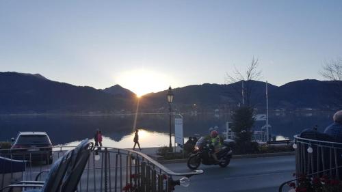 a man riding a motorcycle next to a body of water at Seehotel zur Post in Tegernsee