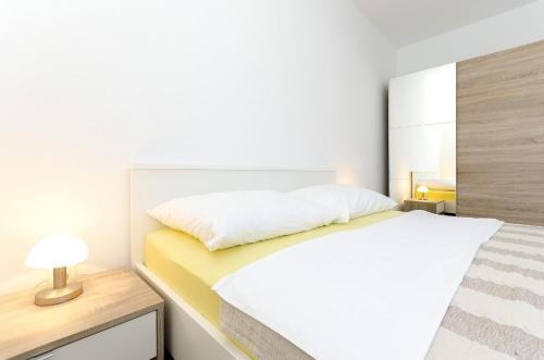 biała sypialnia z łóżkiem i lampką na biurku w obiekcie Apartments New home w mieście Vodice