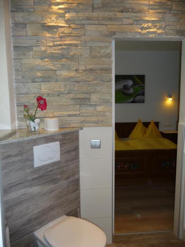 a bathroom with a toilet in front of a stone wall at Familiengasthof St. Wolfgang in Spittal an der Drau