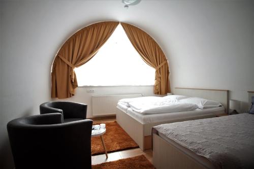 a bedroom with a bed and a window and a chair at Penzion u Pidly in Mariánské Lázně