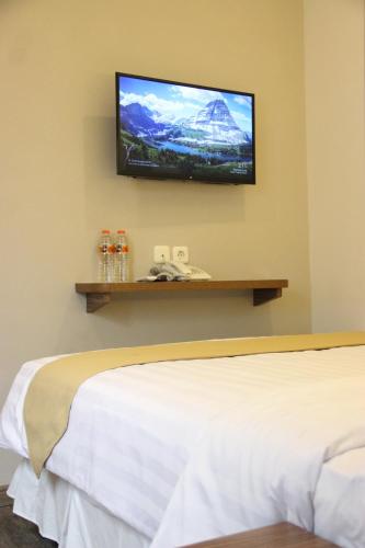 a bedroom with a bed and a flat screen tv on the wall at Front One Cabin Malioboro Jogja in Yogyakarta