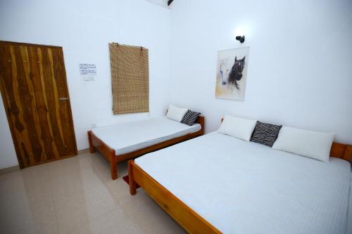 Habitación con 2 camas, puerta y ventana en Amadi Rest, en Kataragama