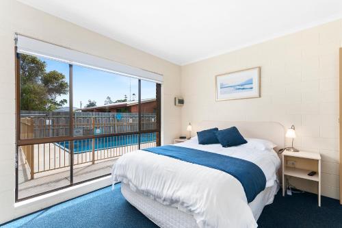 a bedroom with a bed and a large window at Allambi Holiday Apartments in Lakes Entrance