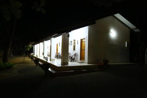 a white building with a porch at night at Amadi Rest in Kataragama
