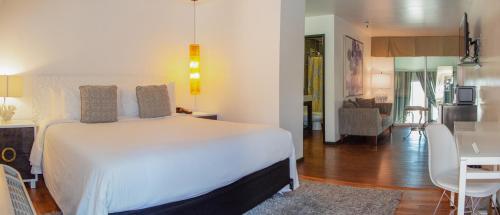 a bedroom with a white bed and a living room at Aqua Soleil Hotel and Mineral Water Spa in Desert Hot Springs