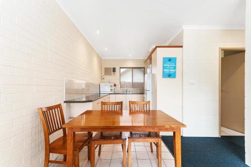 a kitchen with a table and chairs and a refrigerator at Allambi Holiday Apartments in Lakes Entrance