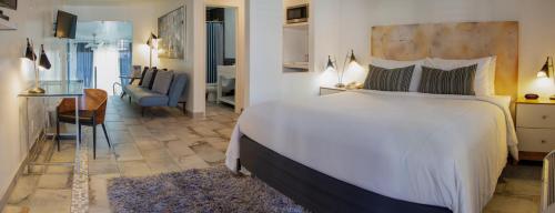 a bedroom with a large white bed and a living room at Aqua Soleil Hotel and Mineral Water Spa in Desert Hot Springs