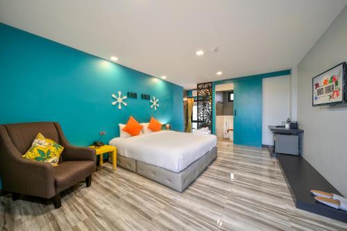 a hotel room with a bed and a chair at Nam Naka Boutique Hotel - SHA Plus in Phuket