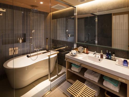 een badkamer met een bad, een wastafel en een douche bij Hotel Ofutei in Fukuyama