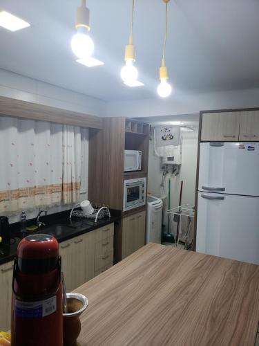 a kitchen with a table and a white refrigerator at 02 suítes em Capão da Canoa - Ed Maui in Capão da Canoa