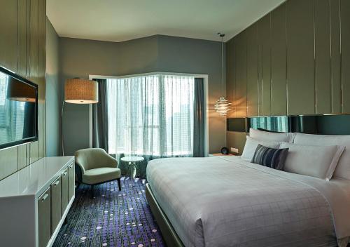 a hotel room with a large bed and a chair at Pullman Kuala Lumpur City Centre Hotel & Residences in Kuala Lumpur