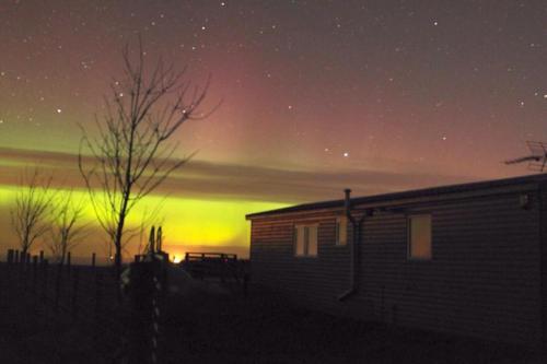 a starry sky with a house and a building at Golden Oak Chalet in Dunbar