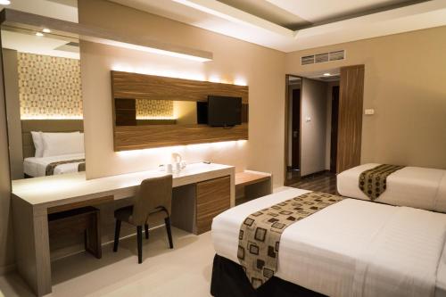 a hotel room with two beds and a desk at Novena Hotel Bandung in Bandung