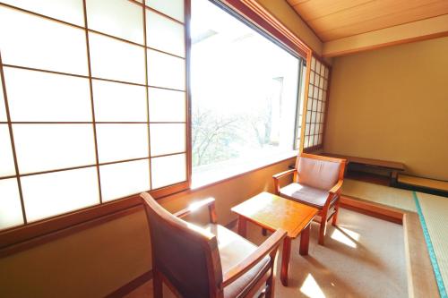 a room with a table and chairs and a large window at Shima Grand Hotel in Nakanojo